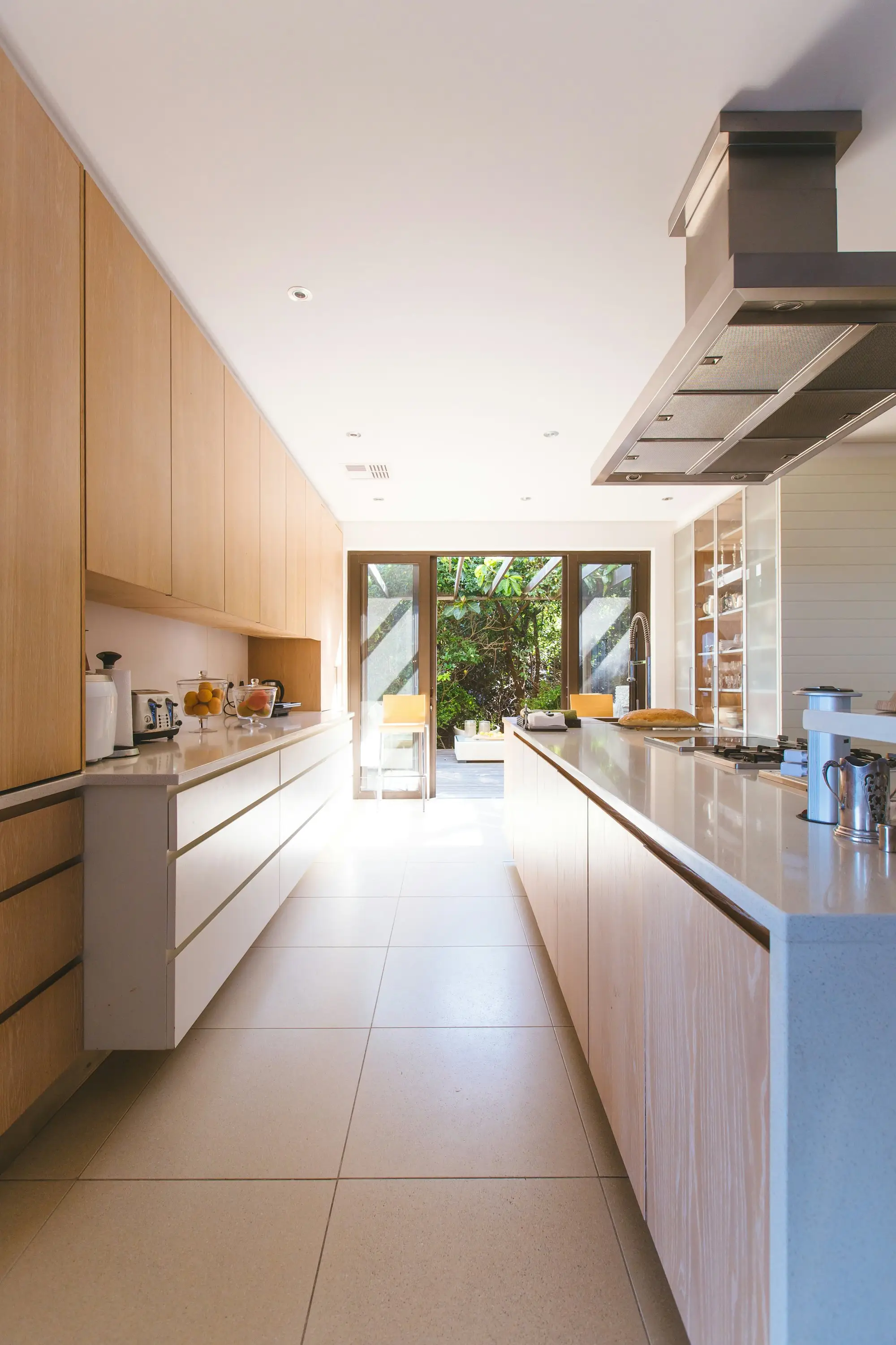 Bright kitchen with a white island, wood floor, and glass doors to a garden